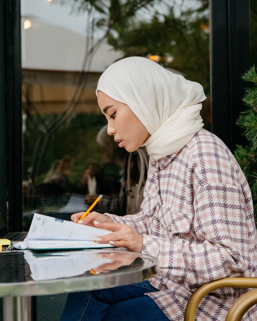 A university student working through a recorded lecture at a desk.